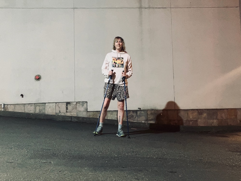 Dielle Lundberg, a white transfeminine person standing with her walking sticks